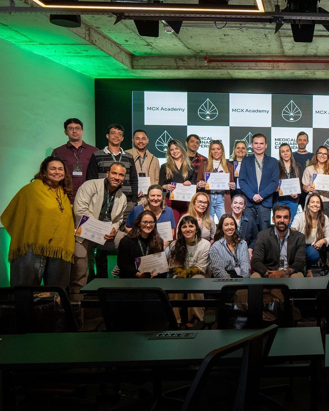Grupo de médicos com certificados diante de um painel da MCX Academy