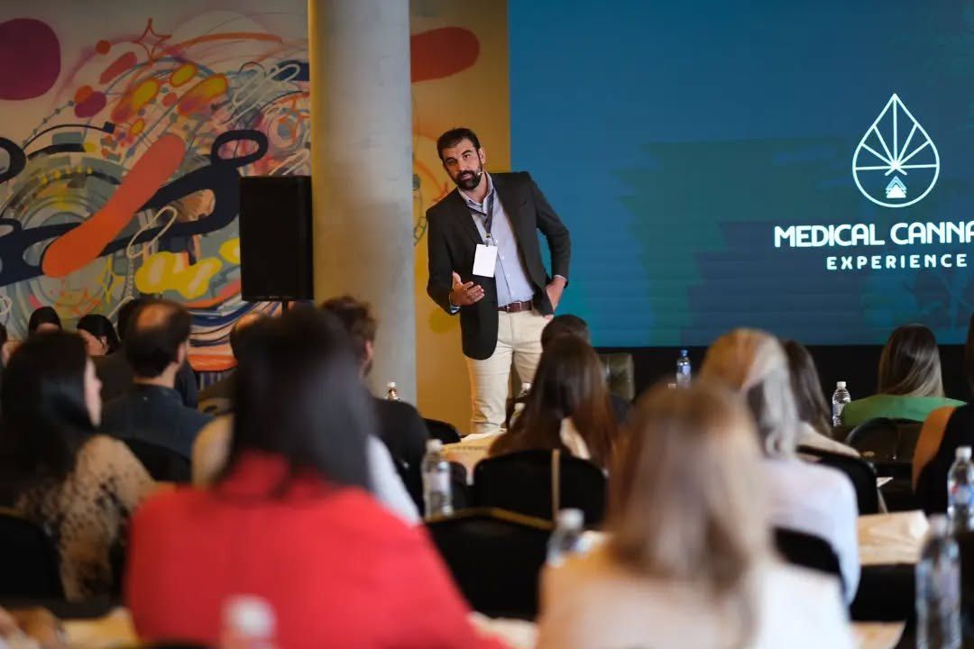 Dr. Plínio Miguel fala em pé diante da turma, com o telão da MCX ao fundo